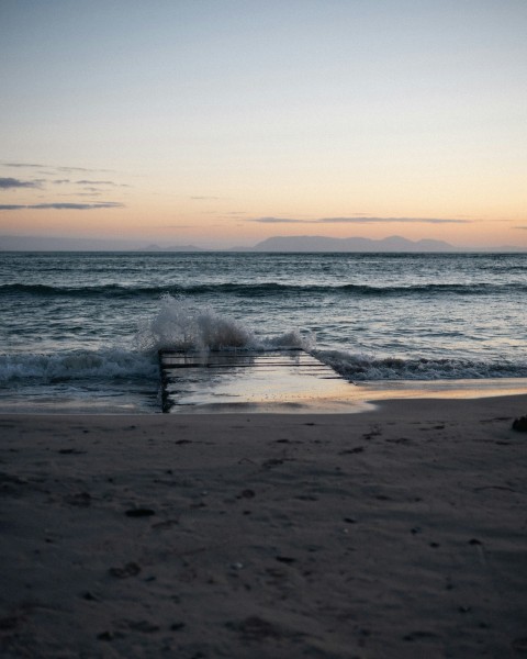 a person standing on a beach next to the ocean 5pU0u