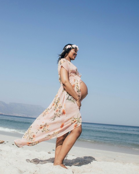 woman in pink and white floral dress standing on beach during daytime