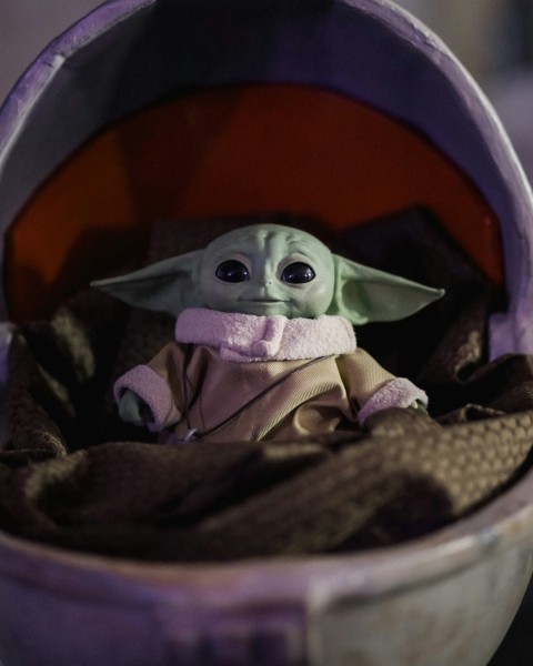 a baby yoda doll sitting inside of a purple container Ix