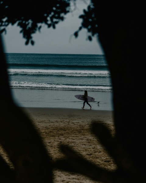 a person walking on a beach with a surfboard