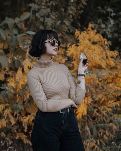 a woman in a turtle neck sweater holding a glass of wine