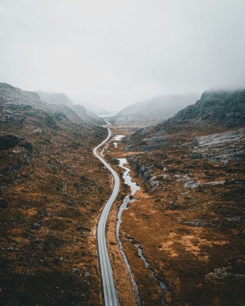 a winding road in the mountains on a foggy day