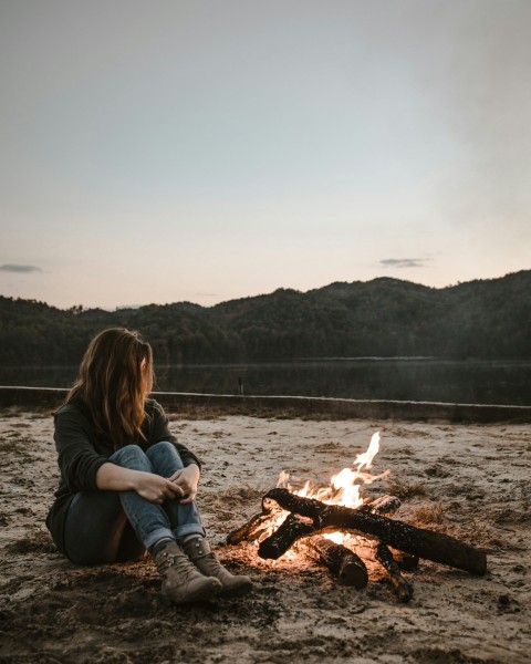 a woman sitting in front of a campfire iAz4OWd