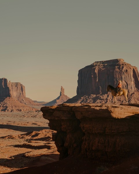 a man riding a horse on top of a cliff