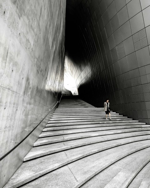 woman in black shirt walking on gray concrete tunnel XtlLO_