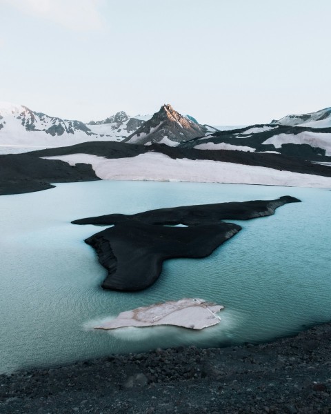 a large body of water surrounded by snow covered mountains