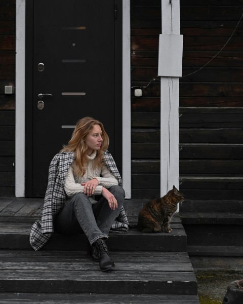 a woman sitting on a porch with a cat