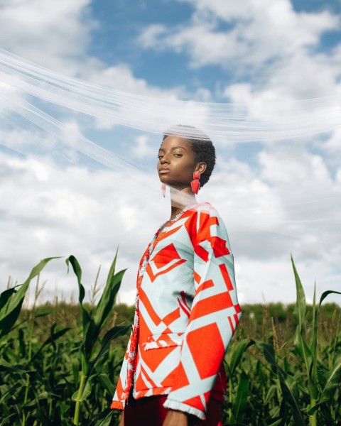 woman in white red and blue floral long sleeve shirt standing on green grass field under