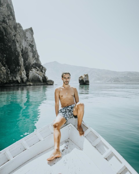 woman in blue and white shorts sitting on white boat on water during daytime