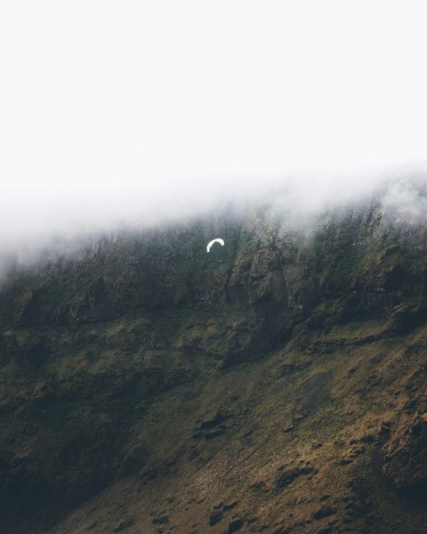 a paraglider is flying over a mountain side