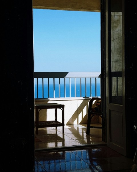 an open door leading to a balcony with a view of the ocean