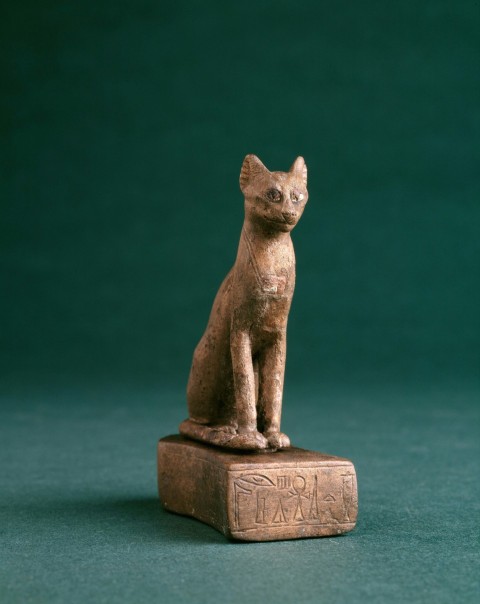 a statue of a cat sitting on top of a wooden block