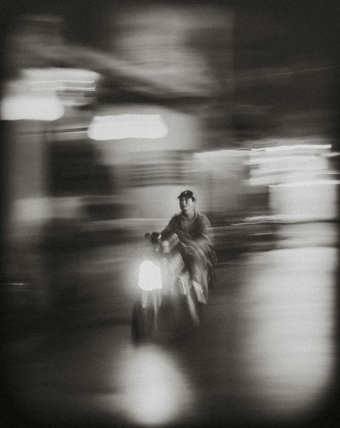 grayscale photo of woman in black jacket and pants walking on street