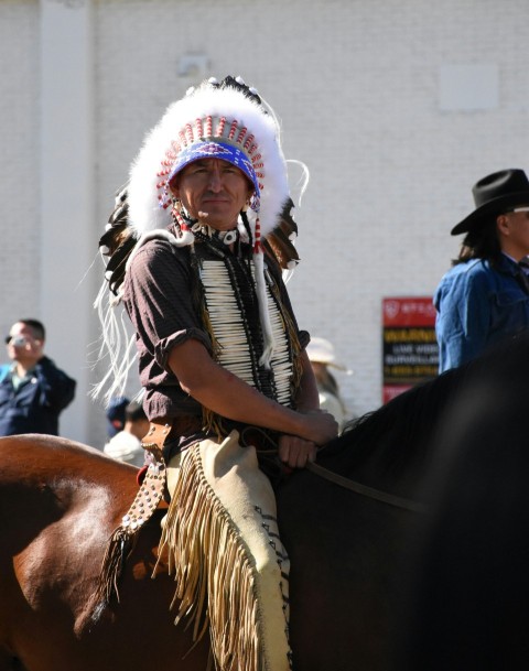 a native american man riding on the back of a brown horse