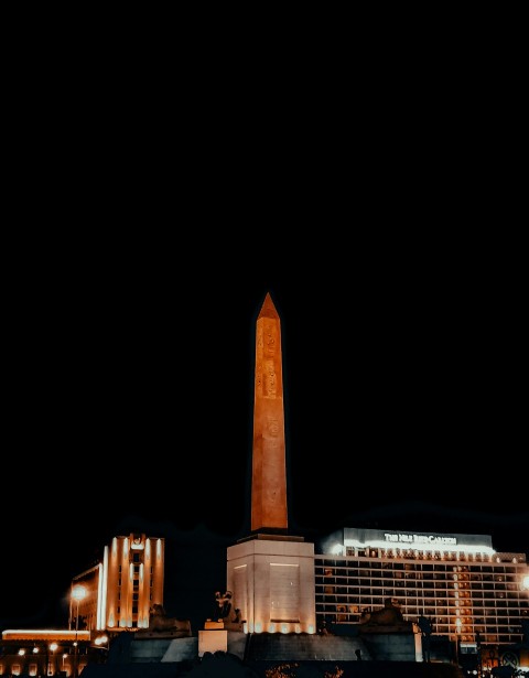 a tall obelisk in front of a building at night