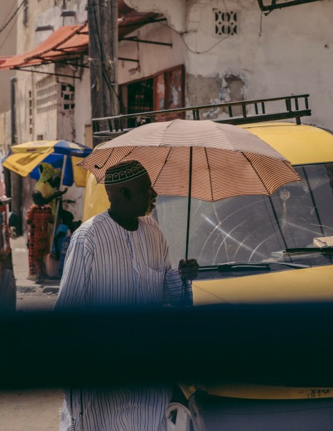 man in white and black striped dress shirt holding umbrella ot