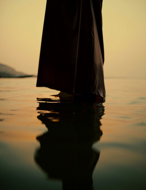 a person standing in the water with a umbrella AQl17