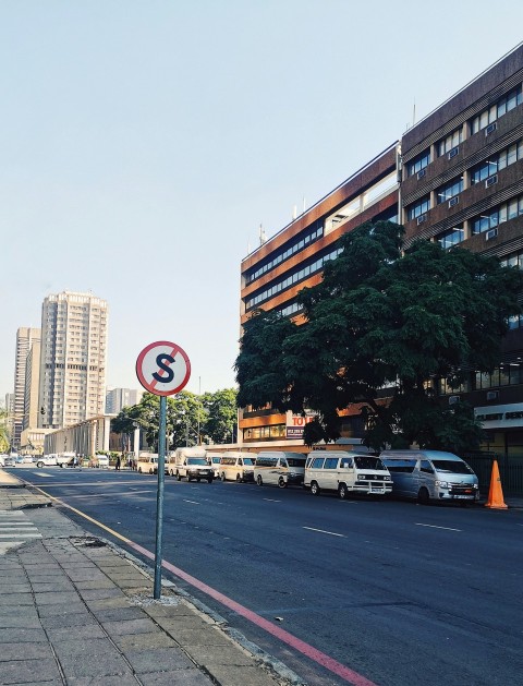 cars parked on side of the road near high rise buildings during daytime