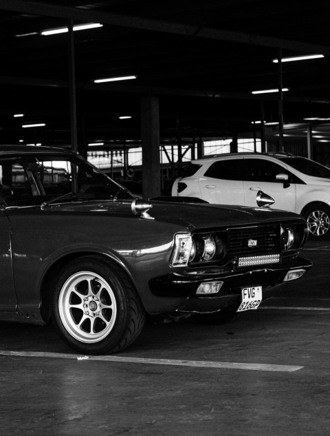 a black and white photo of two cars in a parking garage