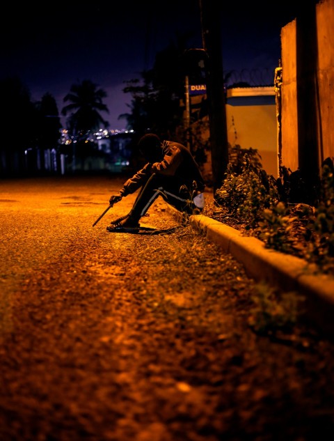 a person sitting on the side of a road at night