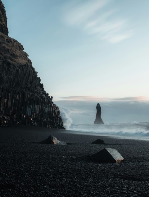 a rocky beach with a large rock formation in the background