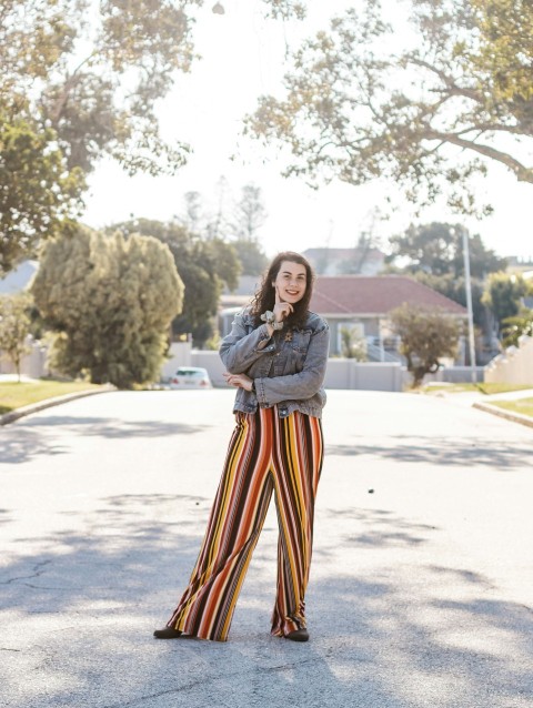 woman in gray long sleeve shirt and orange and black striped skirt standing on gray concrete