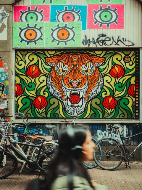 a woman walking past a building with a mural on it