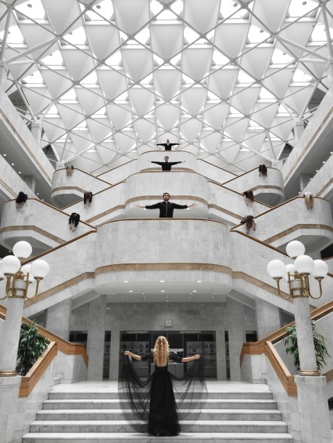 a woman in a black dress standing on a staircase