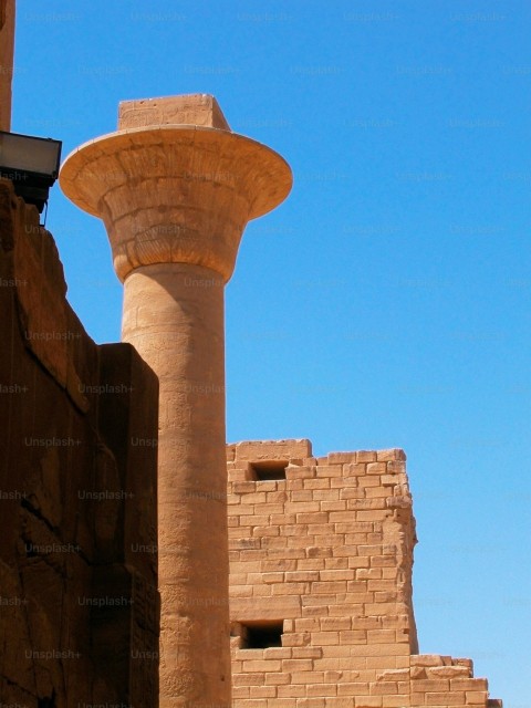 a tall stone pillar next to a brick building