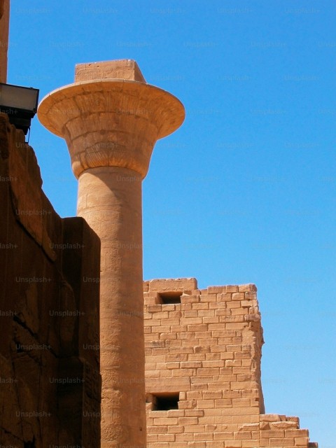 a tall stone pillar next to a brick building