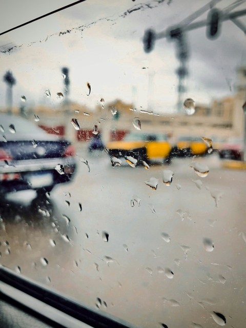 a rain covered window with a view of a parking lot