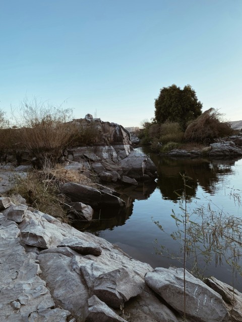 a body of water surrounded by rocks and grass