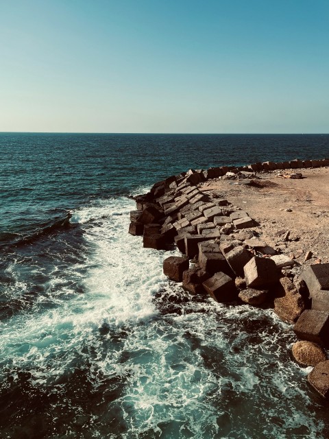 a rocky shore with a body of water next to it