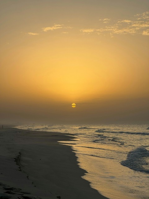 the sun is setting over the ocean on the beach