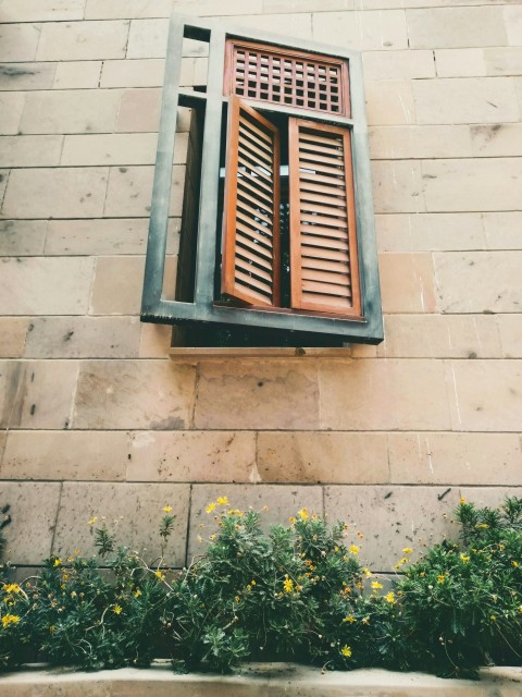 a window on a building with a wooden shutter