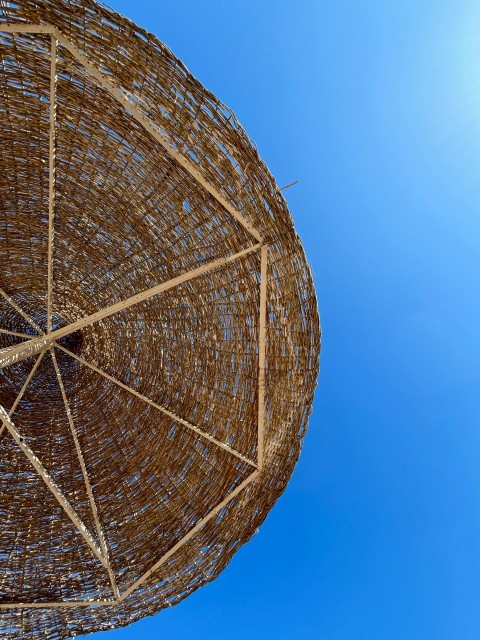 a close up of a bamboo umbrella against a blue sky