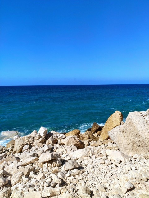 a rocky beach with blue water 4bX