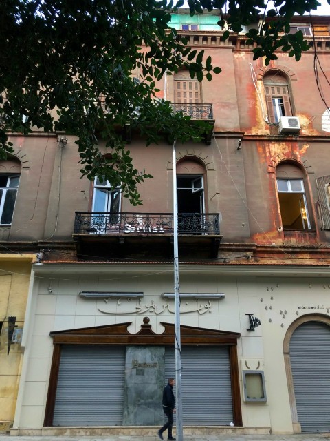 a man walking down a street past a tall building