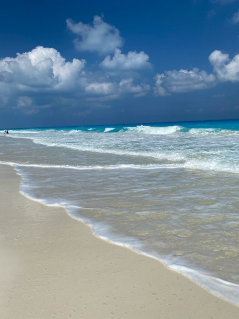 a beach with waves and blue sky