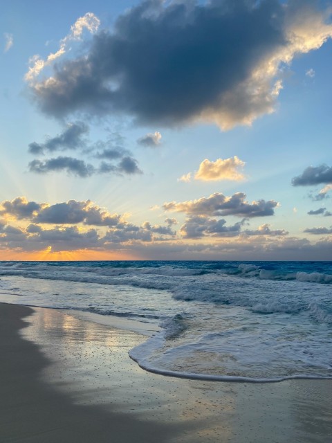 a beach with waves and clouds