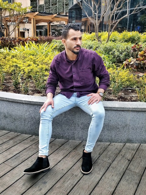 a man in a purple shirt is sitting on a ledge