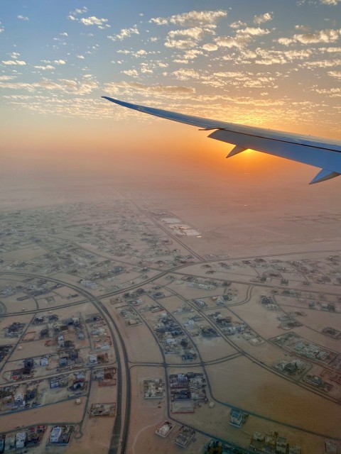 airplane wing above city during sunset