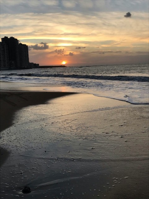 the sun is setting over the ocean on the beach