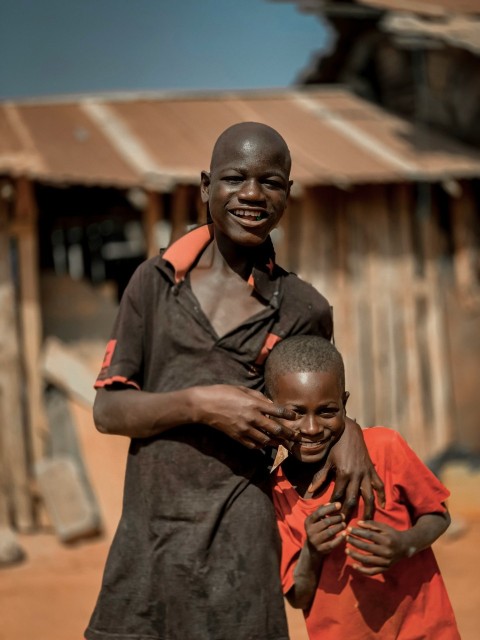 a woman and a child standing in front of a shack