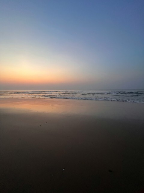 the sun is setting over the ocean on the beach