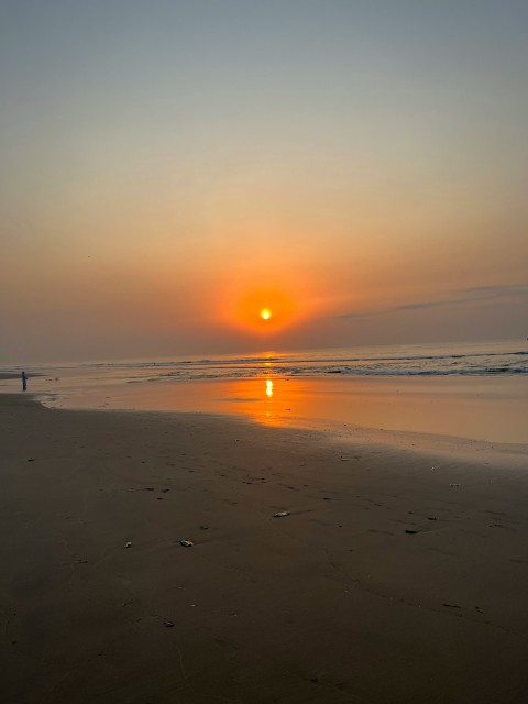 a person walking on a beach at sunset