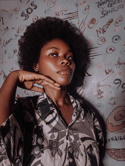 a woman with an afro standing in front of a wall