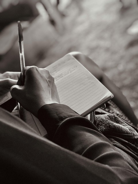 a person sitting down writing on a notebook