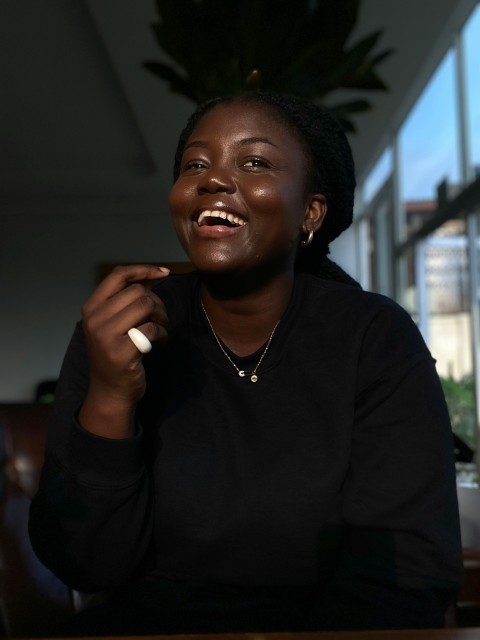 a woman smiles while sitting at a table