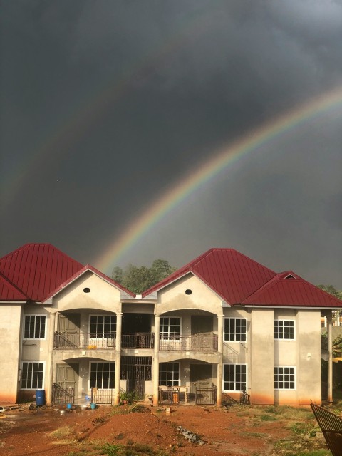 white concrete building under rainbow